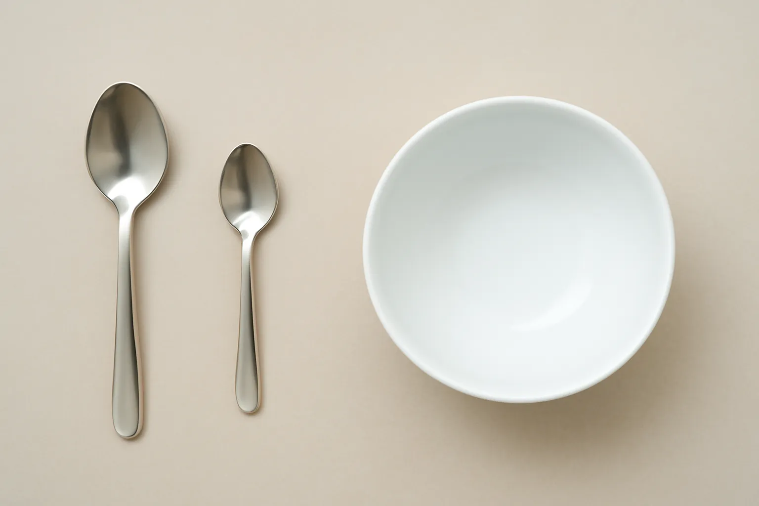 Muỗng canh, muỗng cà phê và một chén ăn cơm đặt cạnh nhau trên bàn